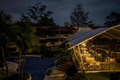 普拉亚科罗纳多Tower Suite Hotel Coronado的一个带游泳池的度假村和一间带桌子和遮阳伞的餐厅