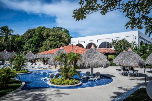 普拉亚科罗纳多Tower Suite Hotel Coronado的一个带游泳池、椅子和遮阳伞的度假村