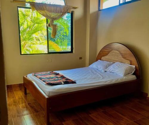 Lago AgrioAmazon Rainforest的卧室里一张带木制床头板的床,卧室里设有窗户