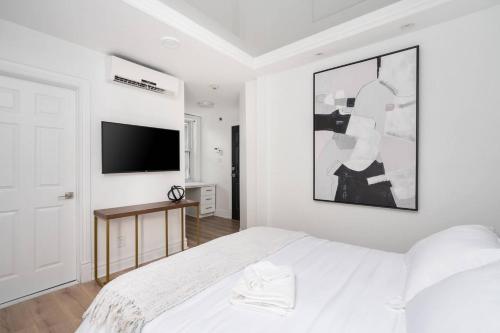 蒙特利尔Penfield Suites的白色卧室配有床和平面电视