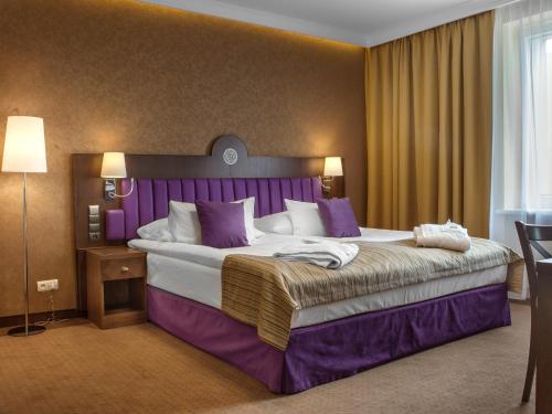 凯尔采GRAND HOTEL Kielce的酒店客房设有一张紫色色调的大床
