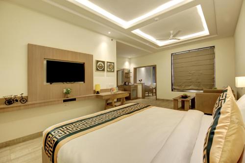 新德里Hotel AMBS suites A family Hotel Near Delhi Airport的酒店客房,配有床和电视