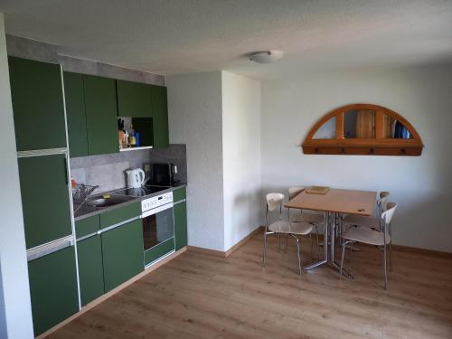 阿施伦Seeblick的厨房配有绿色橱柜和桌椅