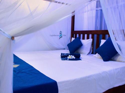 高尔Lighthouse Villa Koggala的一张带蓝色枕头和天蓬的白色床