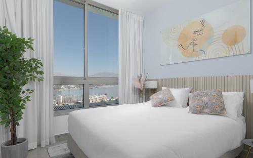 埃拉特Nathan's Suites On The Beach的配有大窗户的客房内的白色床