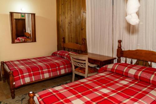 罗索Roxy's Mountain Lodge的酒店客房设有两张床、一张桌子和一张桌子。