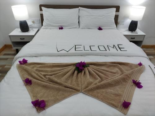 FodhdhooThe Happiness Sun Suites的一张白色的床,上面有迎宾标志