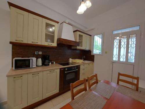 雅典Κατάλυμα στην πόλη Χαλάνδρι的厨房配有白色橱柜、桌子和微波炉