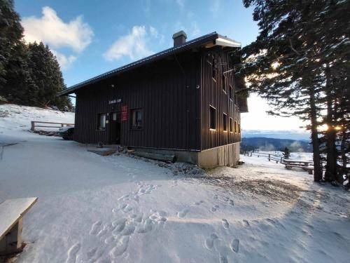 KrivčevoČrnuški dom na Mali planini的雪地中的小屋,雪地中留下脚印