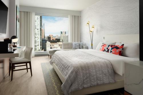丹佛丹佛市中心艾美度假酒店的一间卧室配有一张床、一张书桌和一个窗户。