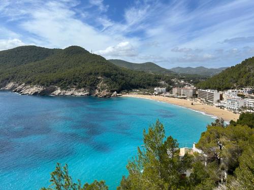 卡拉圣维森特Apartamento en Ibiza的享有蓝水和树木海滩的景致
