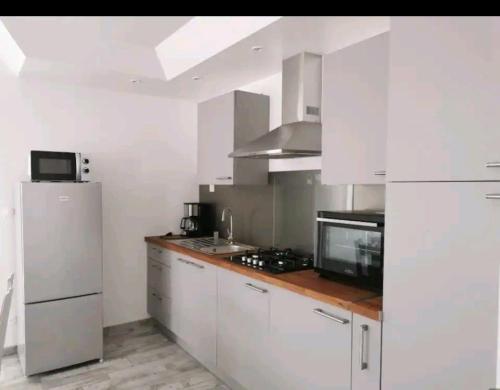 蒙特尔梅La petite maison的厨房配有白色橱柜和冰箱。