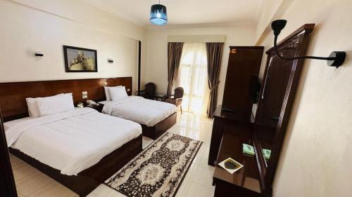 Al KhārijahBadr Hotel & Resort El Kharga的酒店客房设有两张床和电视。