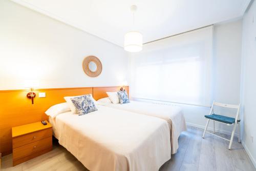 巴利亚多利德Apartamentos GO - Génova Parquesol - Parking Gratuito的一间卧室配有两张床和椅子