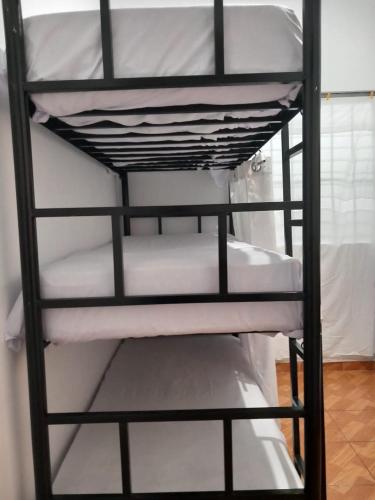 利马PAZ Y BIEN BACKPACKERS - HABITACIÓN COMPARTIDA MIXTA EN MIRAFLORES DE FAMILIA EVANGÉLICA CON PRINCIPIOS Y VALOREs的一张黑色双层床,配有白色床单