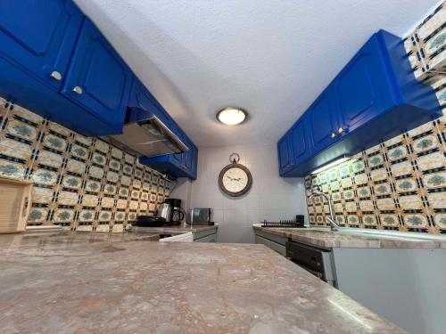 塞萨洛尼基Retro House with Garden in Anopoli的厨房配有蓝色橱柜和墙上的时钟