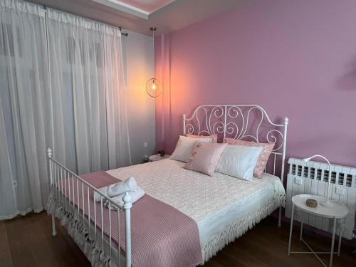 塞萨洛尼基Retro House with Garden in Anopoli的卧室配有白色的床铺和粉红色的墙壁