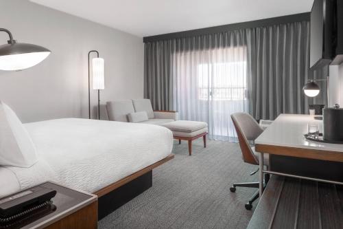 法明顿法明顿万怡酒店的配有一张床和一张书桌的酒店客房