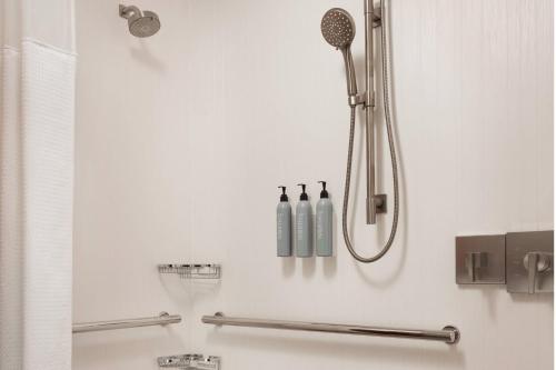 法明顿法明顿万怡酒店的白色浴室设有淋浴,墙上装有瓶子