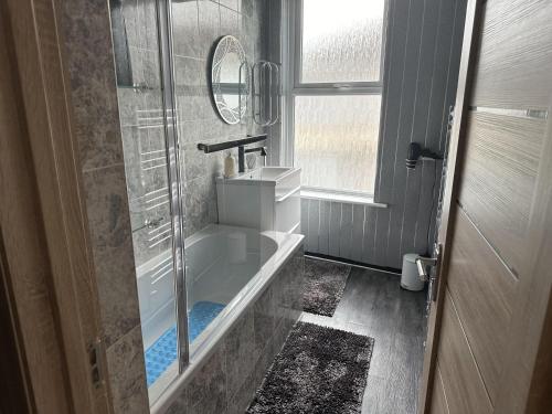 大雅茅斯Impeccable 3-Bed House in Great Yarmouth的带浴缸、水槽和镜子的浴室