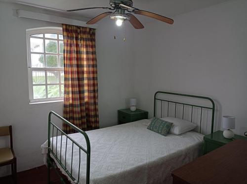 拉日什Rosário Guest House的一间卧室配有一张带吊扇和窗户的床。