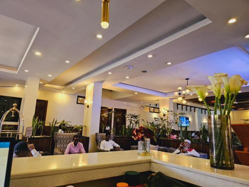 内罗毕Nomad Paradise Hotel的餐厅的大堂,有坐在桌子上的人