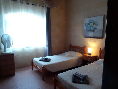 艾因西莱姆Bed and Breakfast Dar Tal-Lumija的一间卧室设有两张床和窗户。