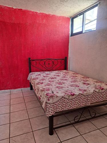 CuautlancingoHabitaciones GERMOMOX的红色墙壁的房间里一张床位