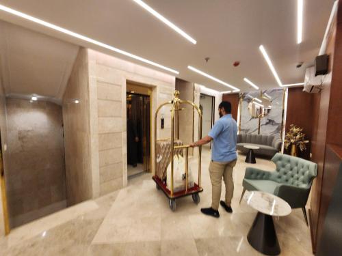 Ash Sharāʼi‘فندق كنف - kanaf hotel的一名男子在酒店大堂推行李车