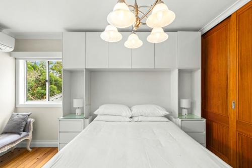 悉尼Elegant 1-Bed with Study by Balmain Wharf的白色卧室配有一张大床和吊灯