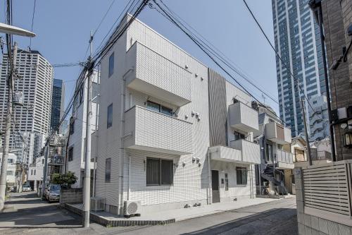 东京Felice Nishi-Shinjuku的城市街道上一座白色的建筑,有高大的建筑