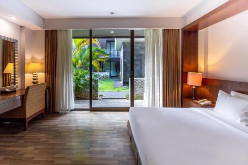乌鲁瓦图巴厘岛大酒店的一间卧室配有一张床、一张书桌和一个大窗户