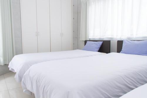 石垣岛Shiraho Villa - Vacation STAY 13688v的卧室内的两张床,配有白色的床单和蓝色的枕头