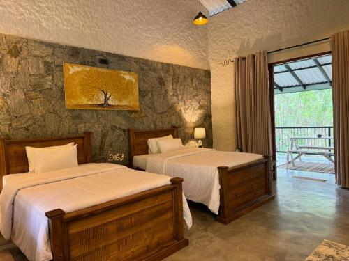 GinigathenaArsulana Eco Lodge & Spa的一间卧室设有两张床和石墙