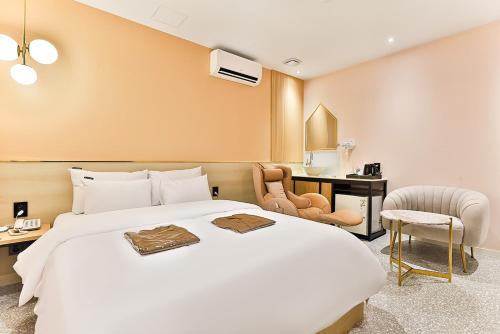 仁川市Brown Dot Hotel Incheon Jakjeon的酒店客房设有一张白色大床和椅子