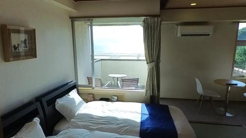 伊喜末HOTEL GREEN PLAZA SHODOSHIMA - Vacation STAY 51989v的卧室在窗户前配有一张床