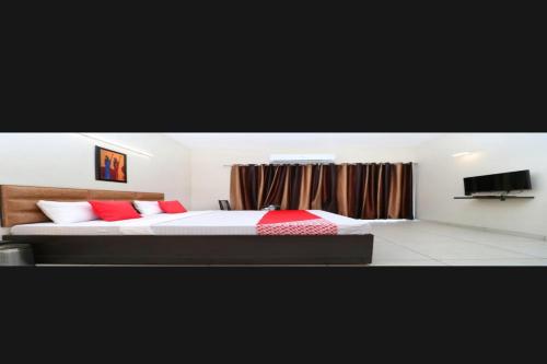 NārnaulOYO Vihan Palace的一间卧室配有一张带红色枕头的床和电视。