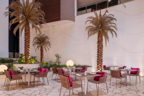 多哈多哈皇冠假日酒店 - 商业公园的一间设有桌椅的餐厅,种植了棕榈树