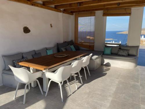 阿基奥斯·索斯蒂斯·米科诺斯Mykonian 4 Bd Ocean Dream House in Agios Sostis的一间带木桌和白色椅子的用餐室