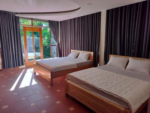 Buôn ErangKhu du lịch Suối Ong的一间卧室设有两张床和窗户。