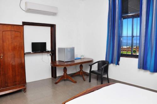 科伦坡Sea View Hotel的客房设有一张桌子、一张床和一个窗户。