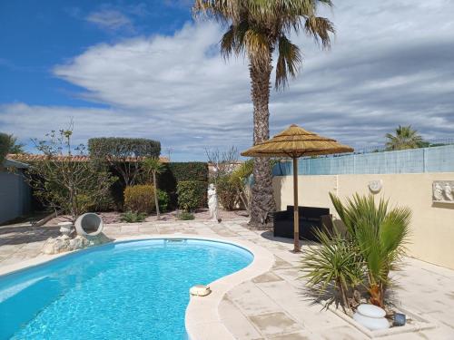 波尔蒂拉盖Villa Manet Portiragnes的一个带遮阳伞和棕榈树的游泳池