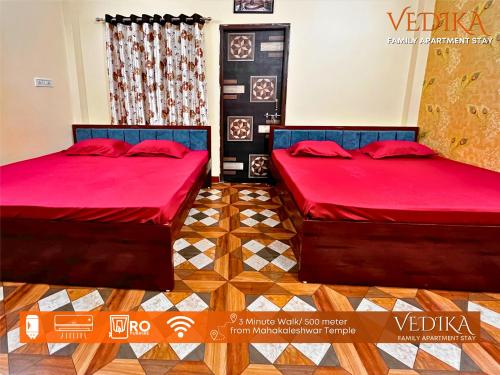 乌贾因Vedika Yatri Grah - Entire Apartment的配有红色床单和木地板的客房内的两张床