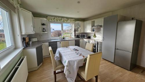 SkeabostDonmar Cottage的厨房配有一张桌子,上面有白色的桌布
