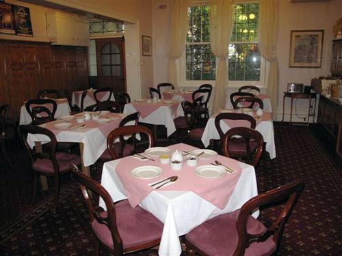 墨尔本乔治亚廷床和早餐旅馆的用餐室配有桌椅和粉红色的桌布