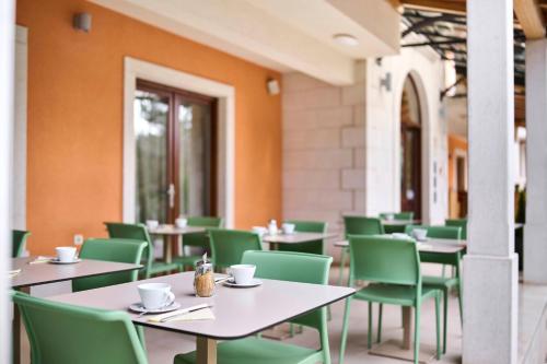 罗维尼Villa Dobravac Wine Estate的一间空餐厅,配有桌子和绿色椅子