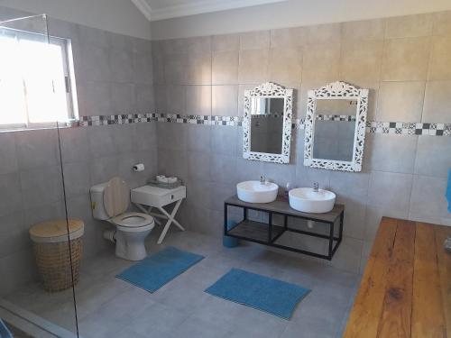MaclearZamenkomst River Lodge的一间带两个盥洗盆、卫生间和镜子的浴室