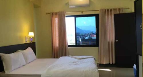 博卡拉Hotel Suite Inn Lodge的一间卧室设有一张床和一个大窗户