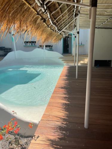 普拉亚TANAWU AIRPORT HOTEL LOMBOK的一个带草屋顶和木板路的游泳池