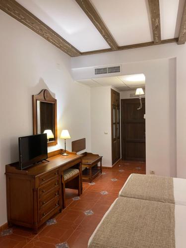 卡索拉Hotel Rural Cazorla Posada del Cordobés的一间卧室配有一张桌子、一台电视和一面镜子
